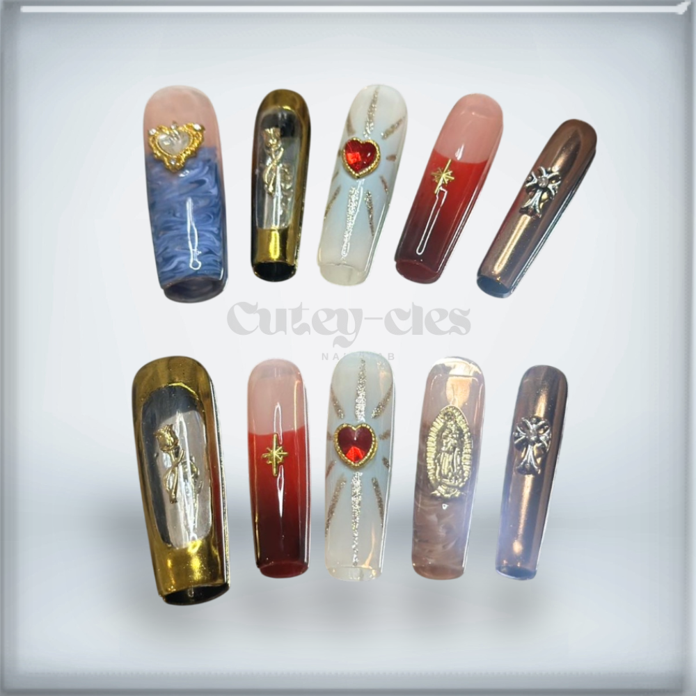 Devotion-inspired press-on nails with gold accents, sacred hearts, and celestial designs displayed on manicured hands.