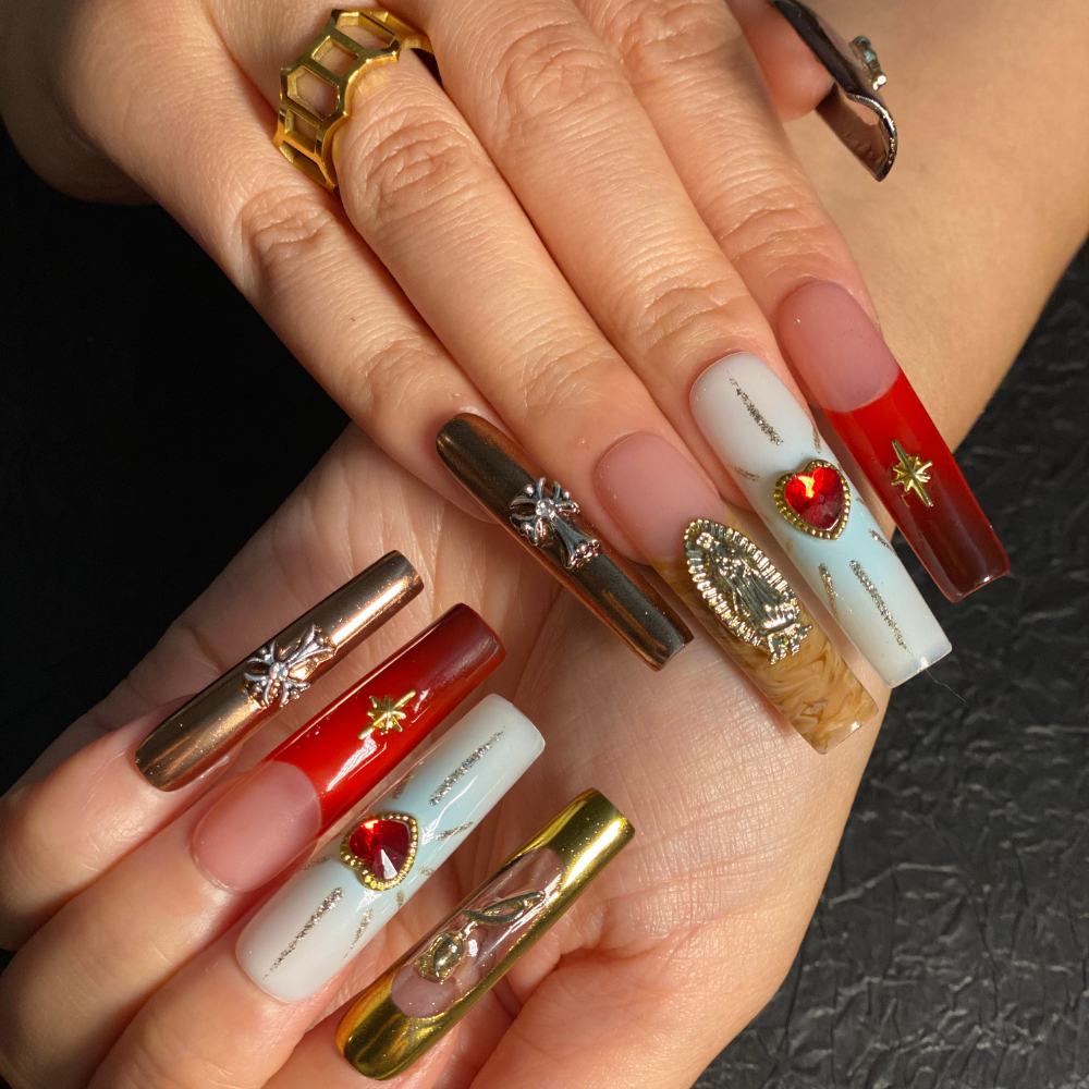 Devotion-inspired press-on nails with gold accents, sacred hearts, and celestial designs displayed on manicured hands.