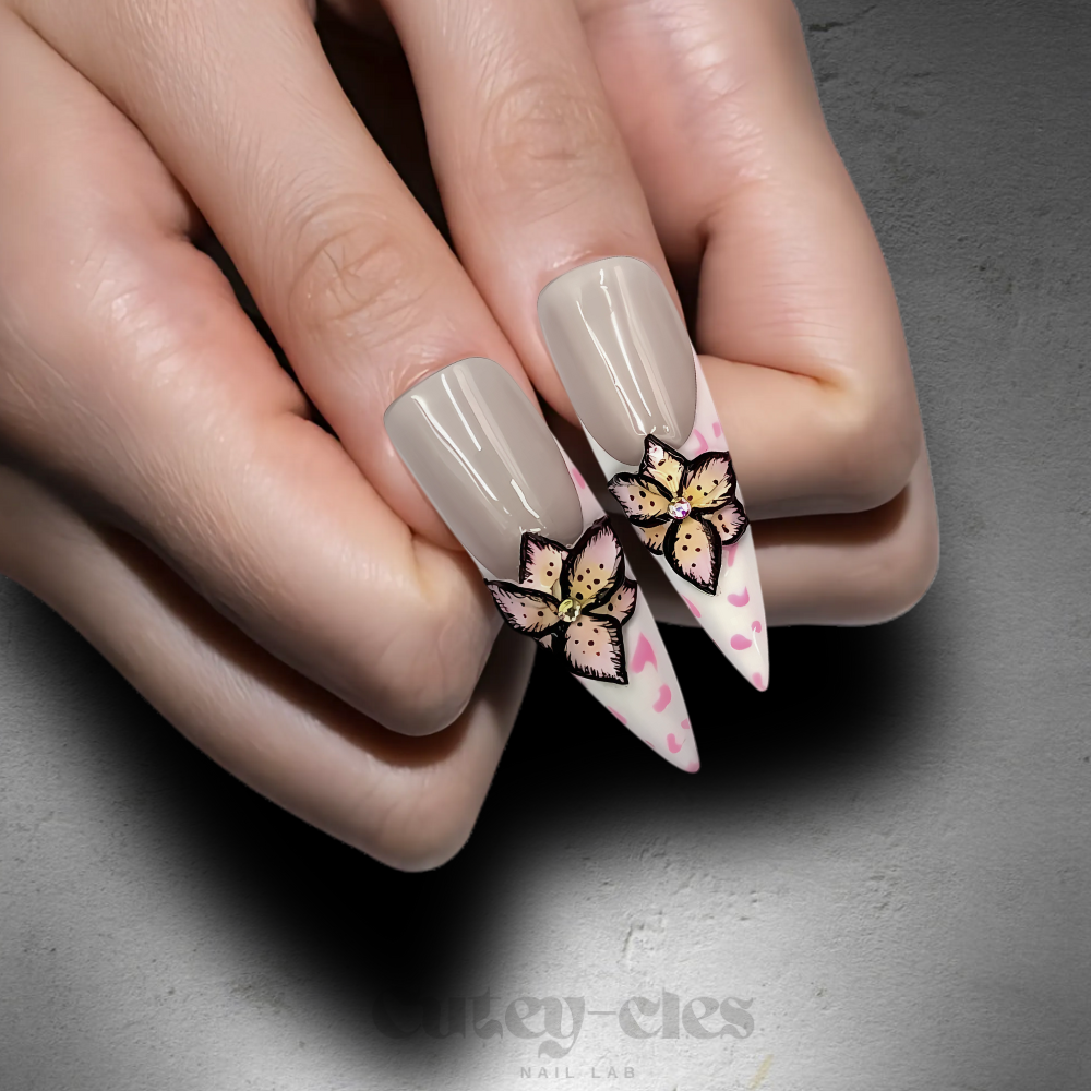 Pink stiletto press-on nails featuring 3D butterfly and floral embellishments with metallic accents, perfect for fairycore or glam nail art enthusiasts.