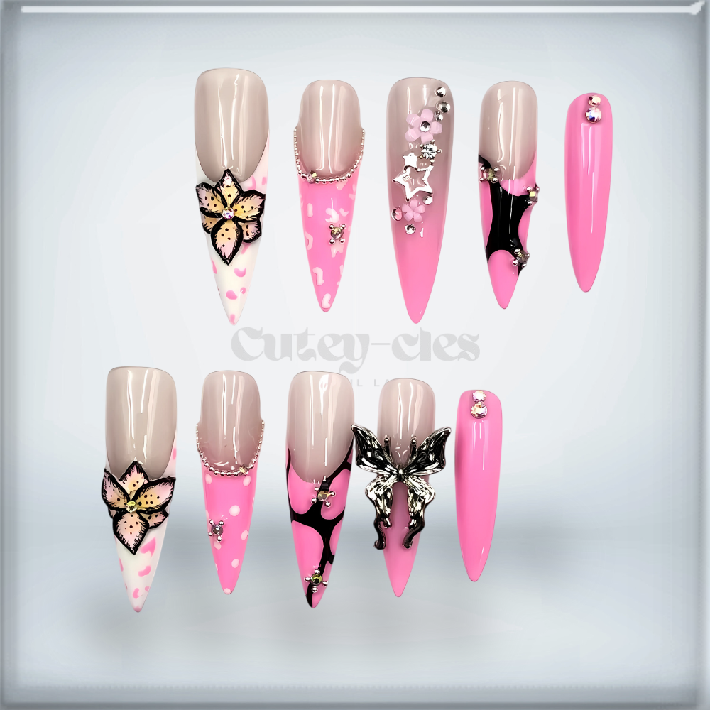Pink stiletto press-on nails featuring 3D butterfly and floral embellishments with metallic accents, perfect for fairycore or glam nail art enthusiasts.