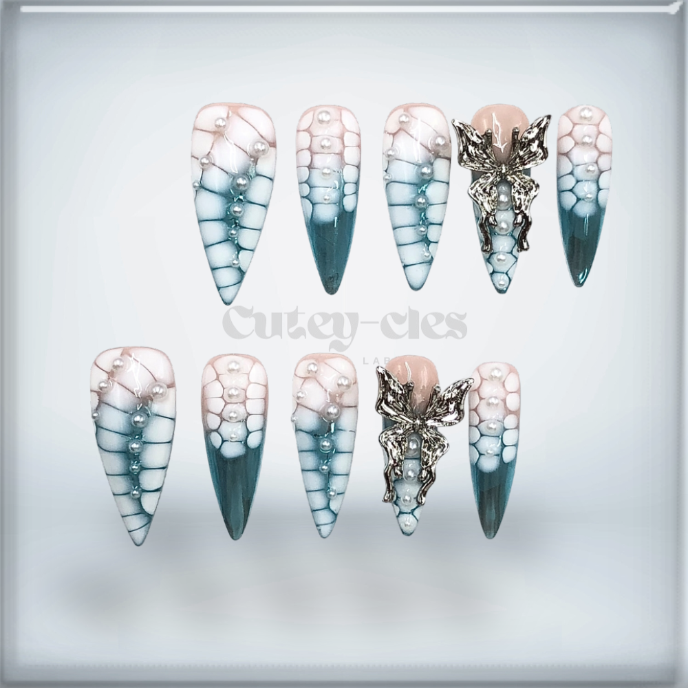 Stiletto press-on nail set with teal-to-nude gradient, dragon scale texture, pearls, and a 3D silver charm.