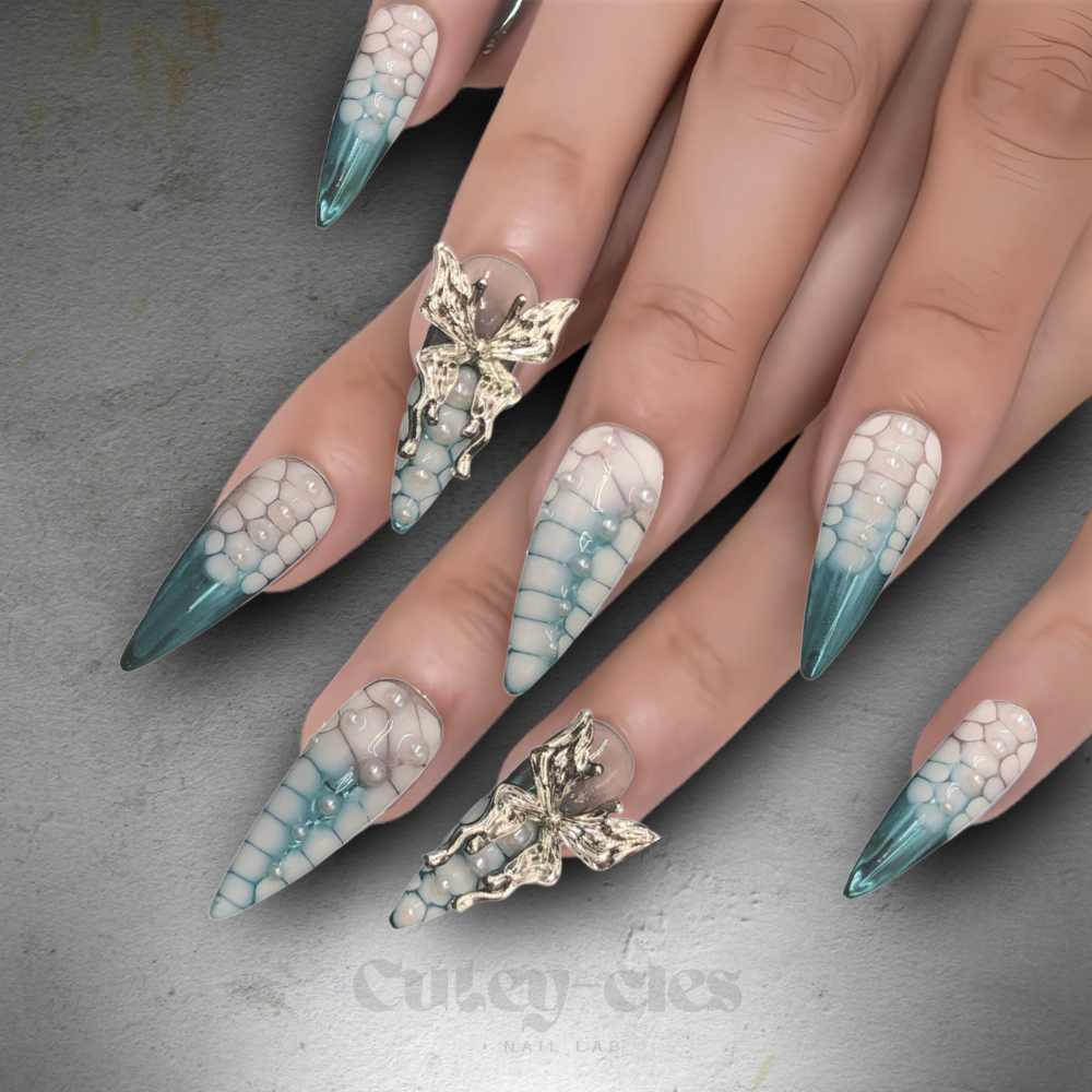 Stiletto press-on nail set with teal-to-nude gradient, dragon scale texture, pearls, and a 3D silver charm.