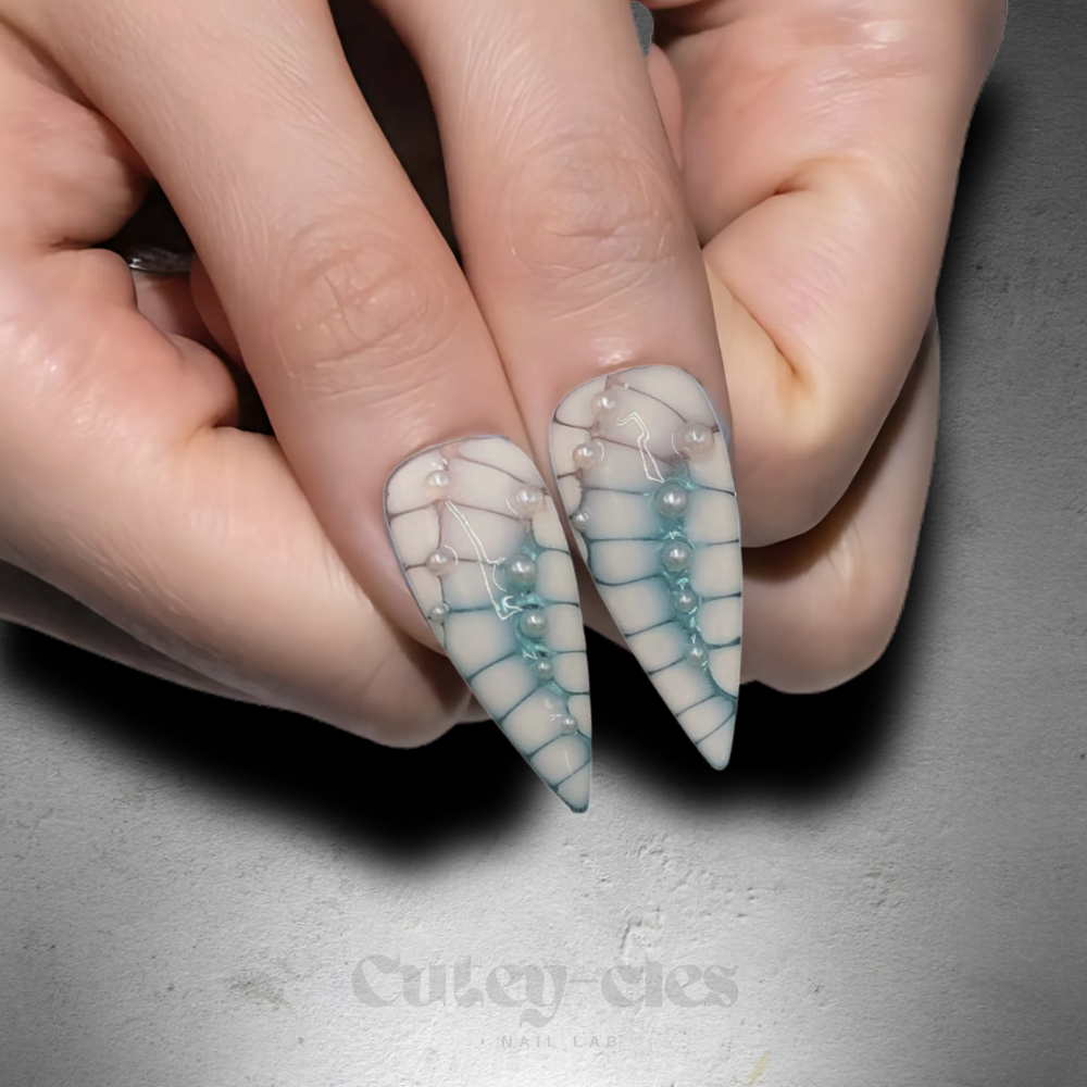 Stiletto press-on nail set with teal-to-nude gradient, dragon scale texture, pearls, and a 3D silver charm.