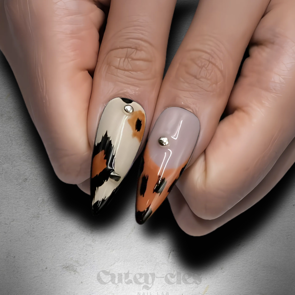 stiletto press-on nails featuring animal print, gold studs, and glossy finish