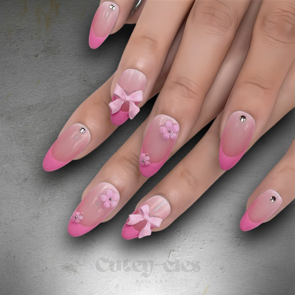 Press-on nails with pink French tips, floral decorations, bows, and gems for a cute and feminine look.