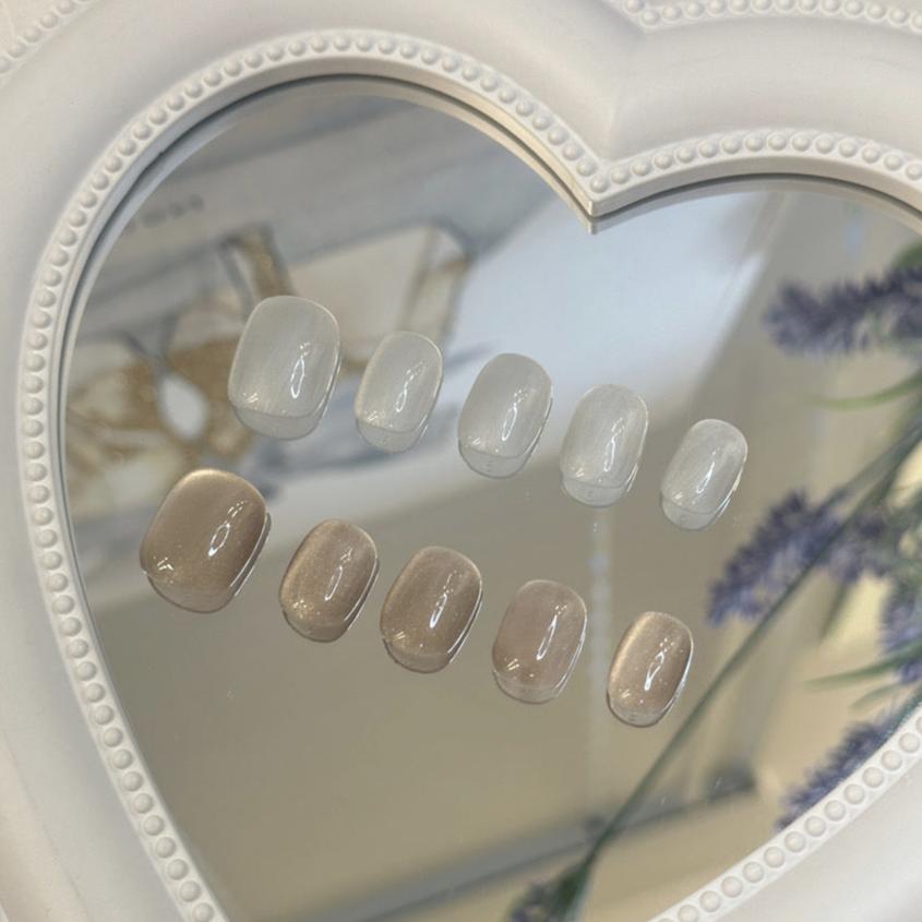 Handmade neutral and white short oval press-on nails with a minimalist, soft finish.