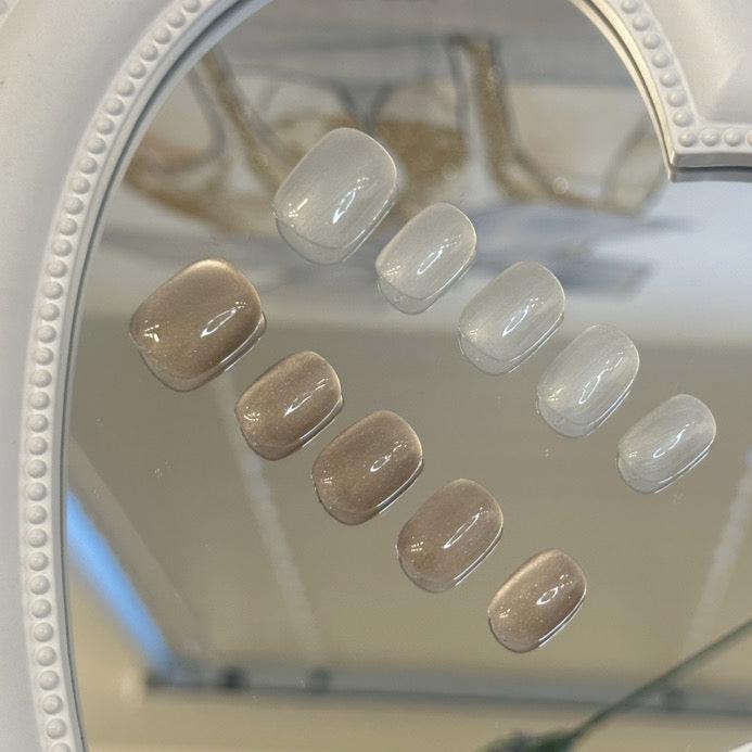 Handmade neutral and white short oval press-on nails with a minimalist, soft finish.