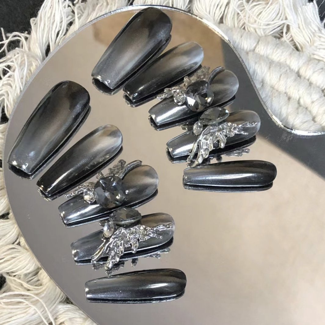 Chrome fake nails with gothic floral jewelry accents on select nails, creating a dark and elegant look.