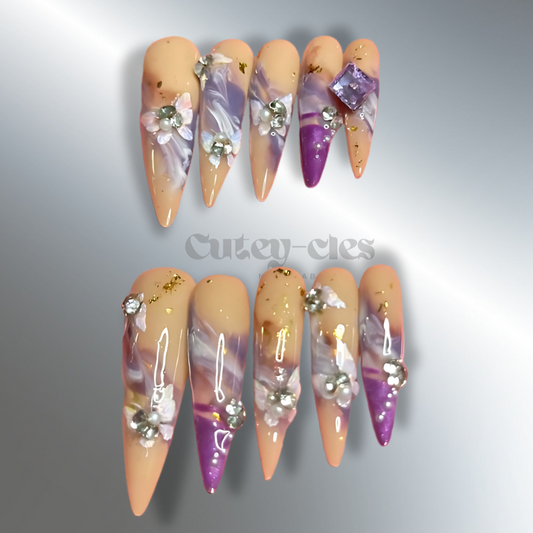 3XL long stiletto press-on nails in peach and lavender with 3D floral embellishments and marbled Art Nouveau-inspired design.