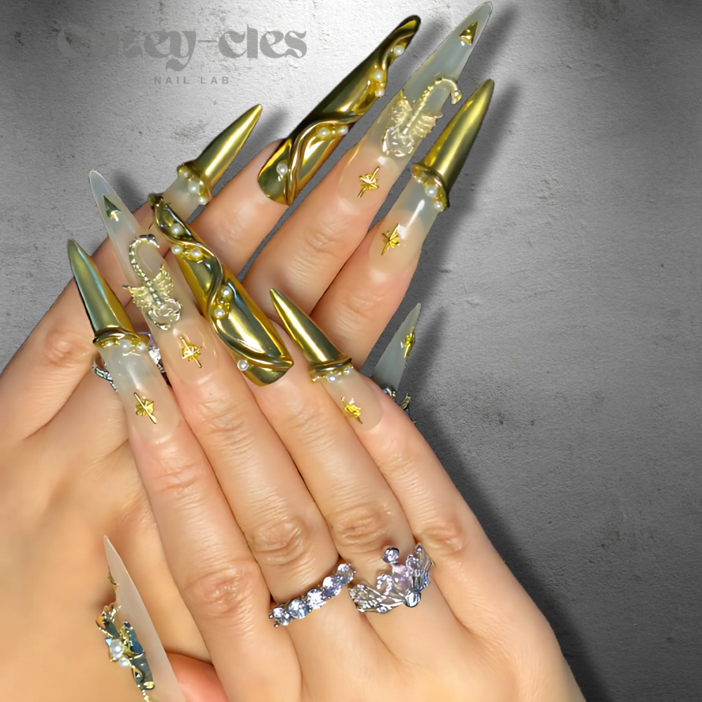 Long stiletto press-on nails with gold metallic sculpted designs, gothic star motifs, pearl accents, and a translucent base for an elegant and bold look.