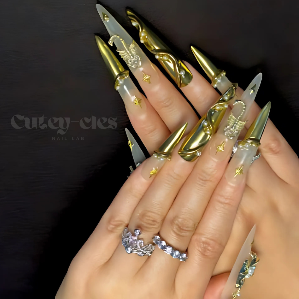 Long stiletto press-on nails with gold metallic sculpted designs, gothic star motifs, pearl accents, and a translucent base for an elegant and bold look.