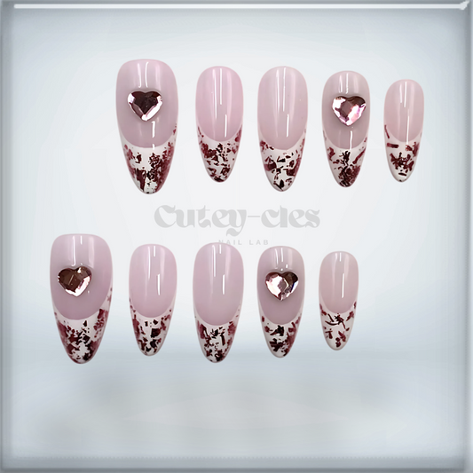 rose gold foil French tip press-on nails with heart accents and a glossy finish.