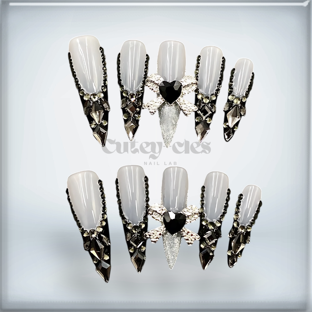 luxury gothic stiletto press-on nails featuring black crystals, silver accents, and a bold 3D heart embellishment for a high-fashion look.