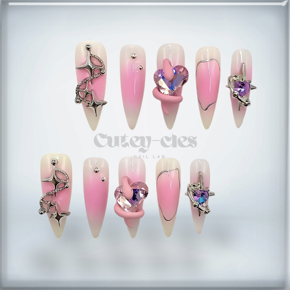 Pink gradient press-on nails with crystal heart embellishments and metallic star accents.