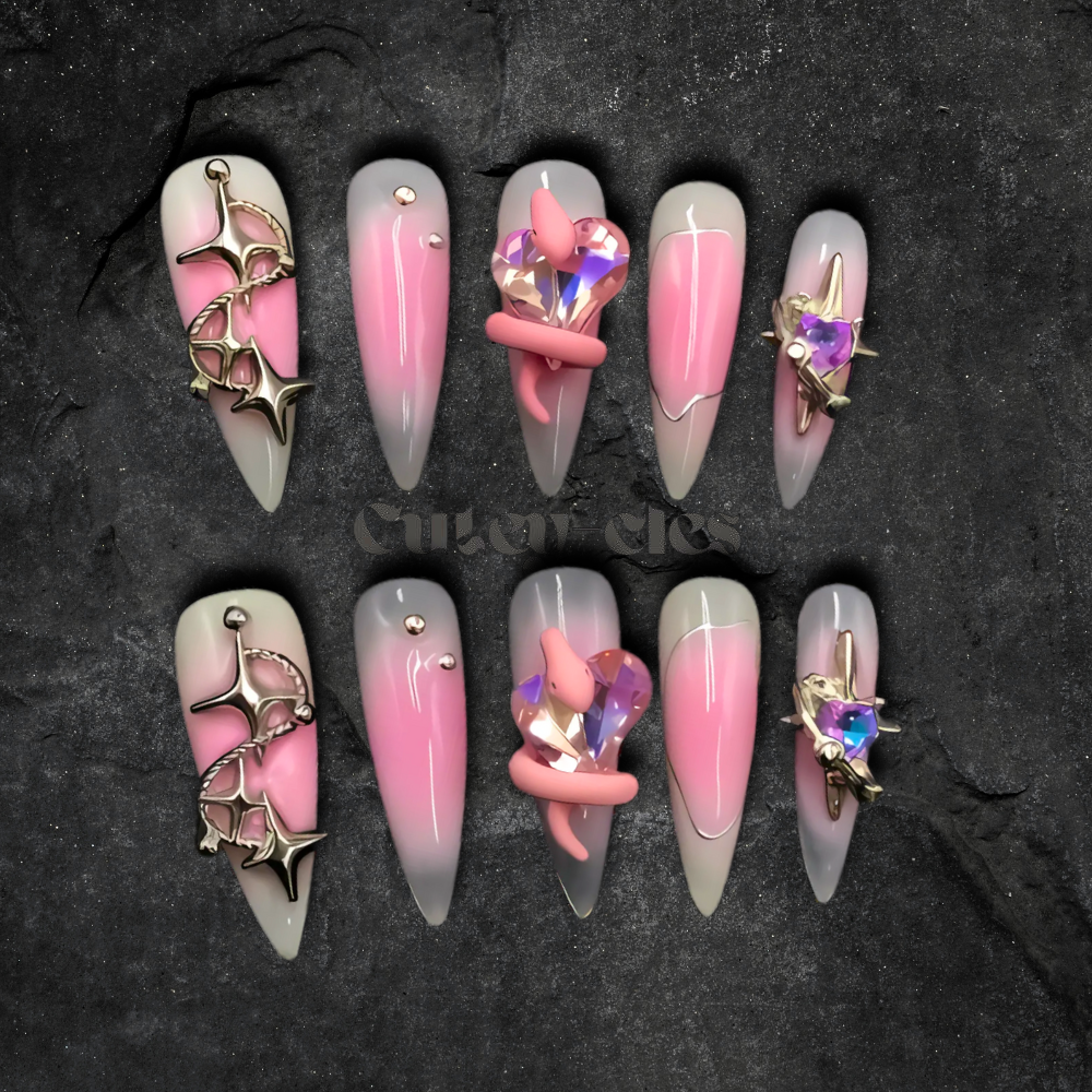 Pink gradient press-on nails with crystal heart embellishments and metallic star accents.