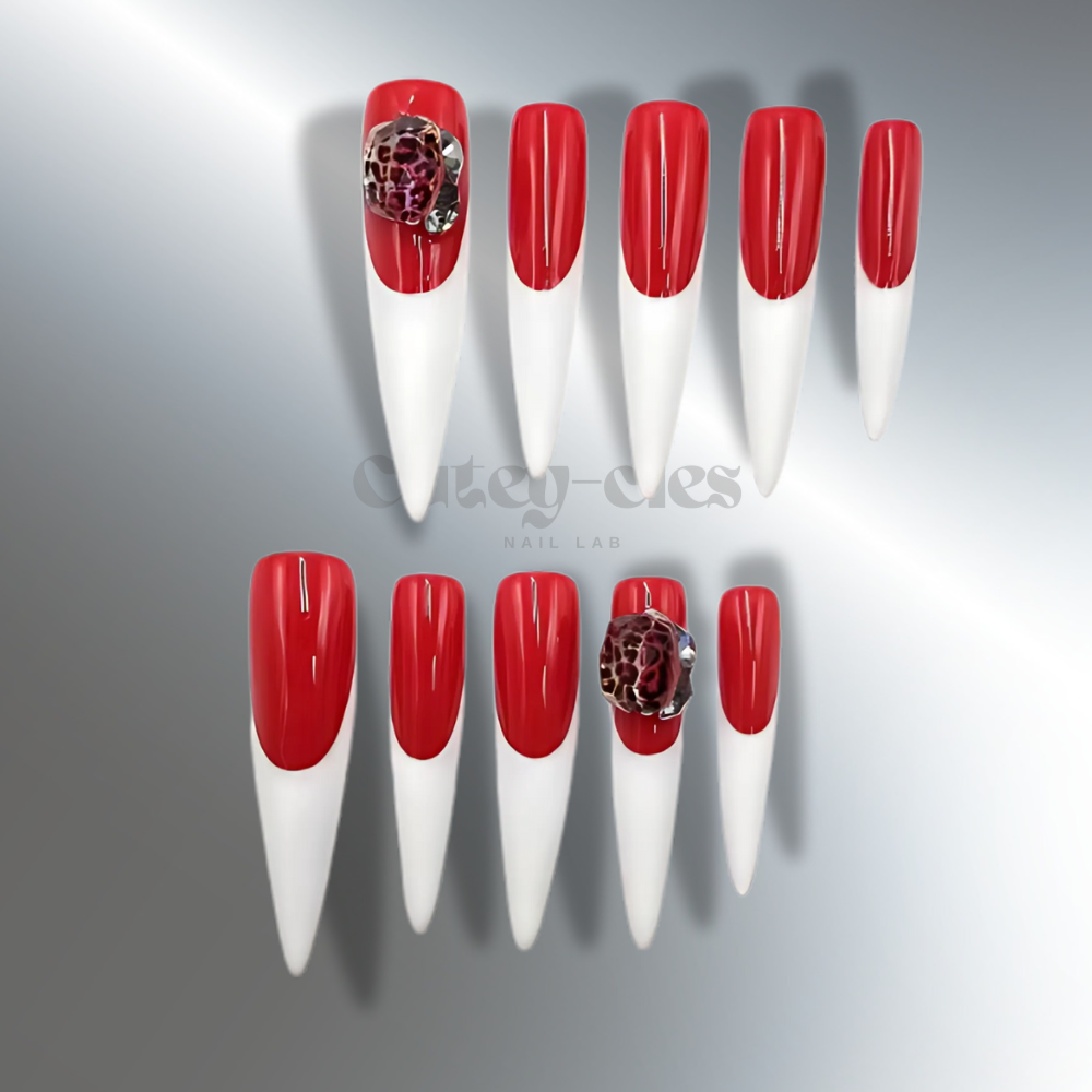 3XL stiletto nails with bold red polish and white tips, featuring a floral embellishment for a dramatic and stylish design.