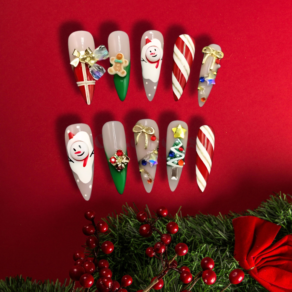 Christmas-themed stiletto press-on nails with 3D designs, including candy canes, gingerbread men, bows, and festive ornaments in red, green, and white.