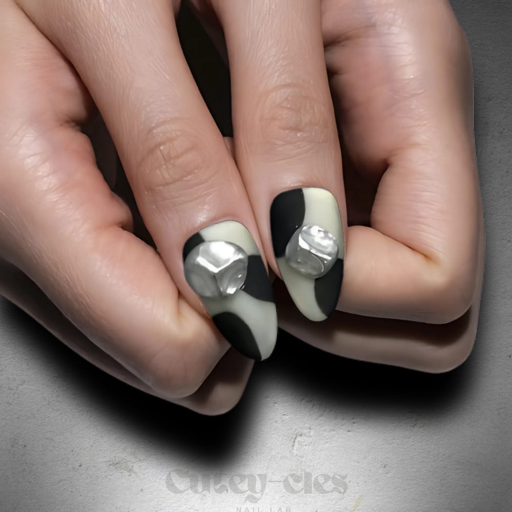 Short almond press-on nail set featuring a black-and-white monochrome design with 3D metallic embellishments.