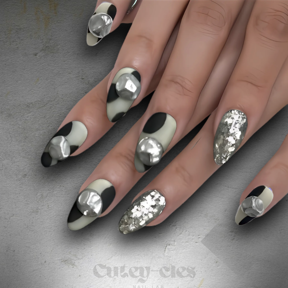 Short almond press-on nail set featuring a black-and-white monochrome design with 3D metallic embellishments.