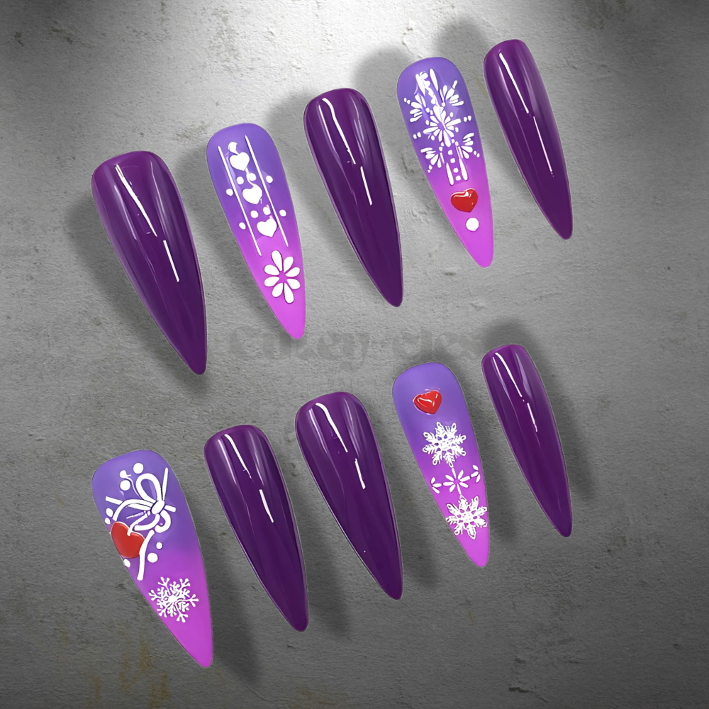 Purple ombre stiletto holiday press-on nails featuring snowflake patterns, heart accents, and glossy finish for a winter-inspired design.