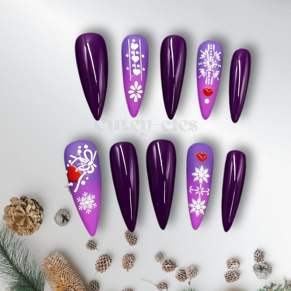 Purple ombre stiletto holiday press-on nails featuring snowflake patterns, heart accents, and glossy finish for a winter-inspired design.