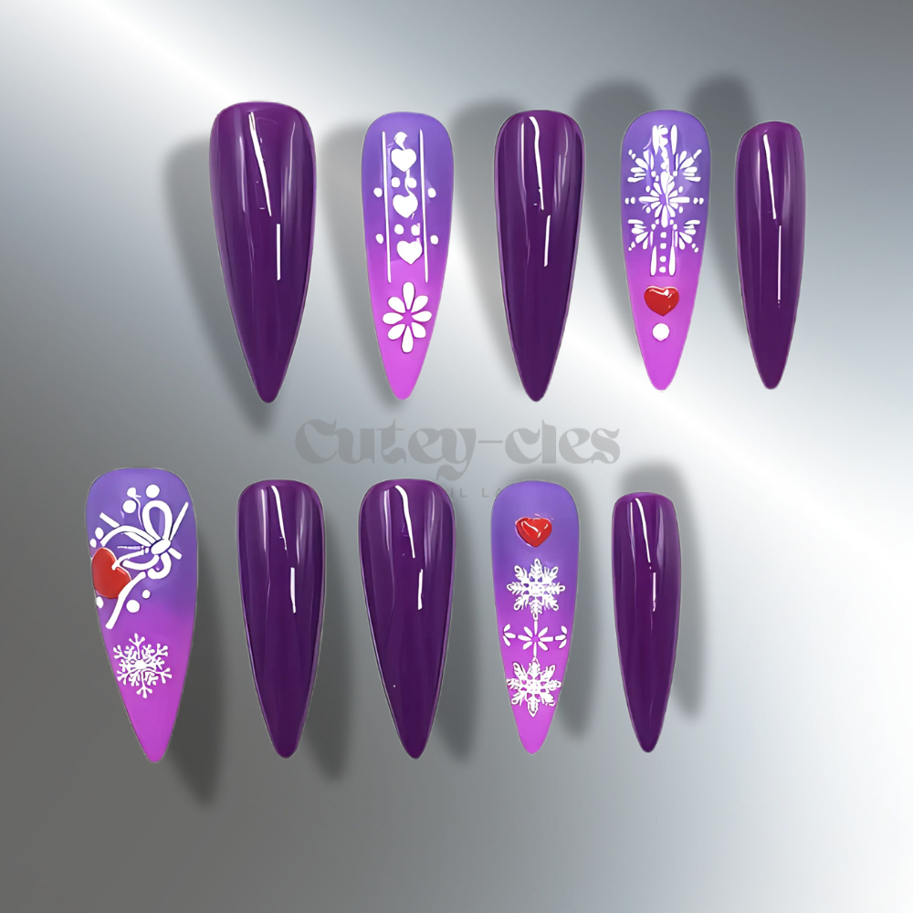 Purple ombre stiletto holiday press-on nails featuring snowflake patterns, heart accents, and glossy finish for a winter-inspired design.