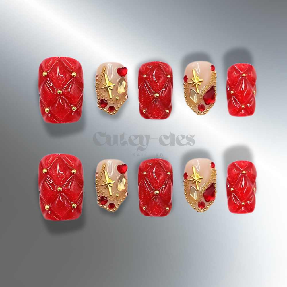 Red quilted press-on nails with gold accents and gemstone embellishments, designed for the holiday season.