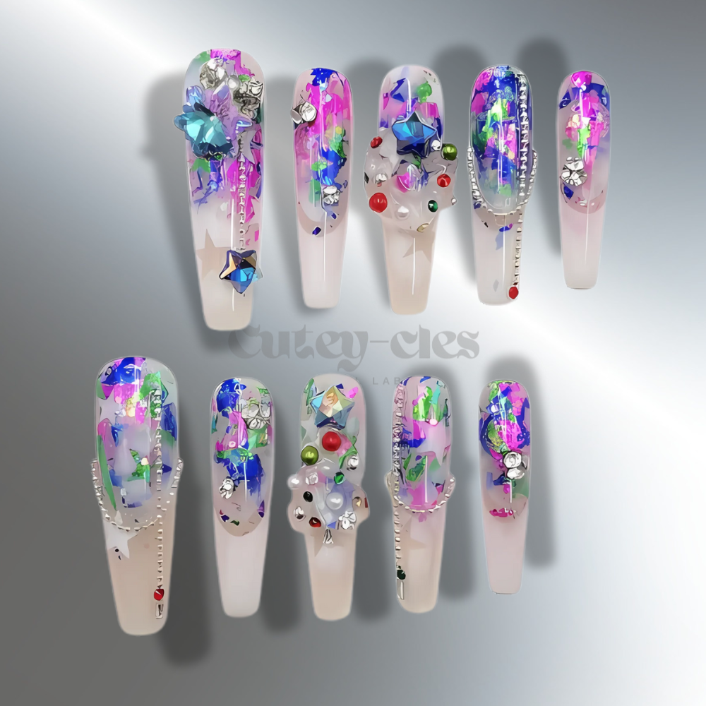 Vibrant 3D press-on nails with abstract holographic patterns, colorful rhinestones, and iridescent foil accents on a transparent base.