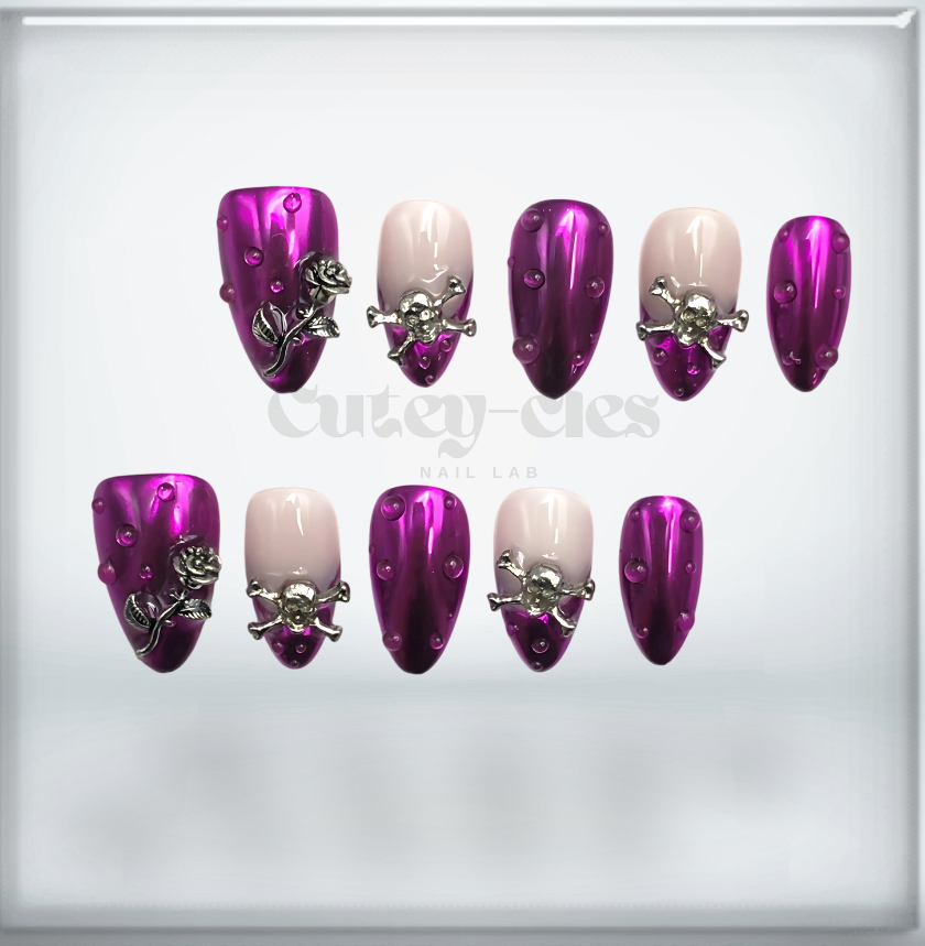 metallic purple press-on nails with gothic silver skull and rose embellishments, featuring a dark glam aesthetic.