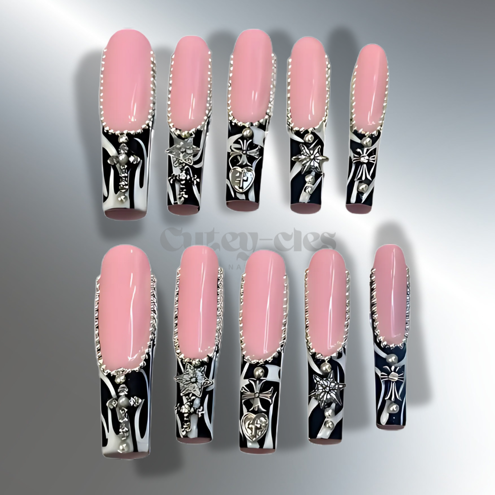 Pink and black 3xl press-on nails with zebra print tips, silver charms, and intricate accents for a bold and stylish look.