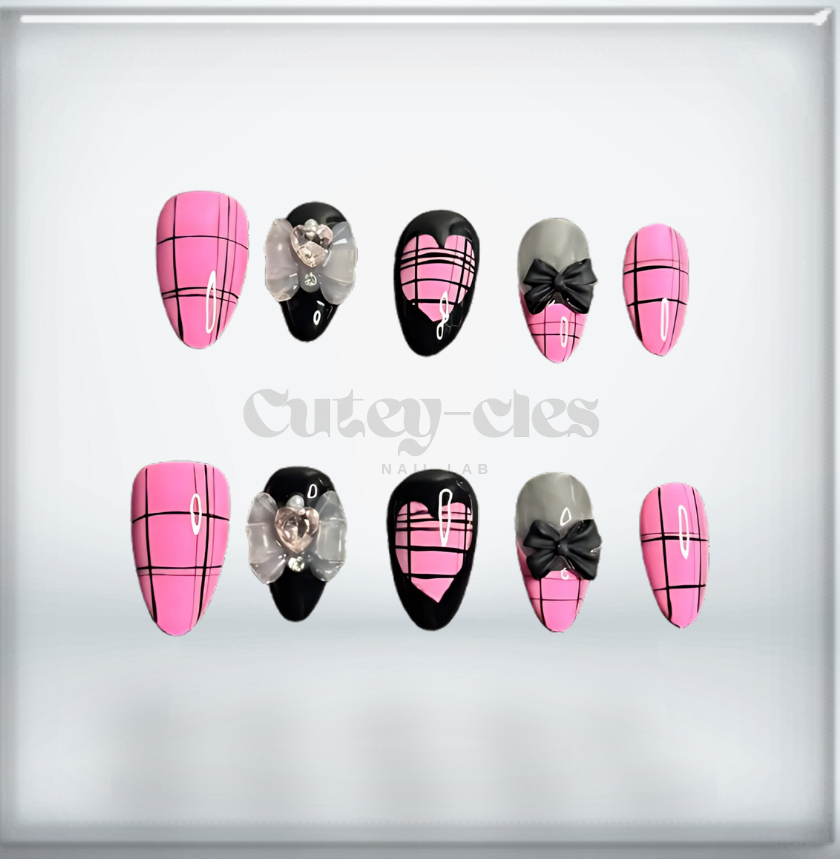 almond press-on nails featuring a pink and black plaid pattern with glossy finishes, bow embellishments, and heart details.