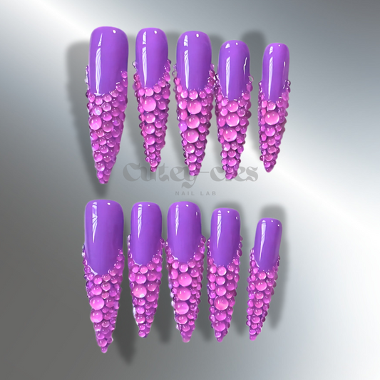 Vibrant 3D purple rhinestone stiletto nails, showcasing luxurious design with high-gloss polish and bold crystal embellishments