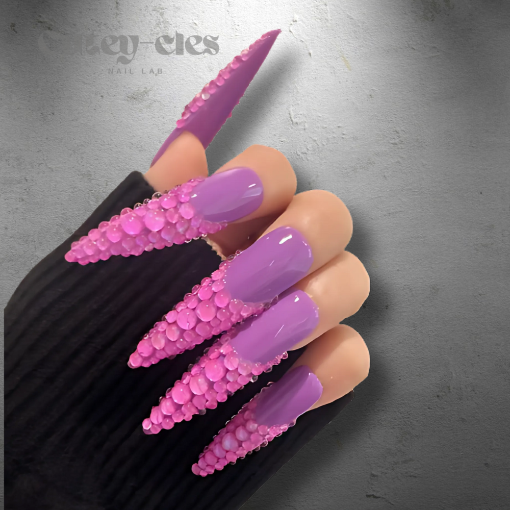 Vibrant 3D purple rhinestone stiletto nails, showcasing luxurious design with high-gloss polish and bold crystal embellishments