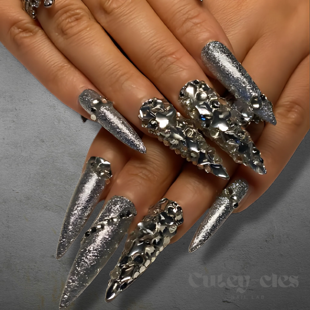 2XL silver stiletto press-on nails with sparkling glitter and rhinestone embellishments, shown on hands with luxurious rings